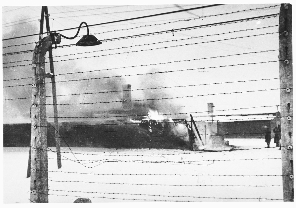 View through the barbed wire fence of the burning Kanada barracks