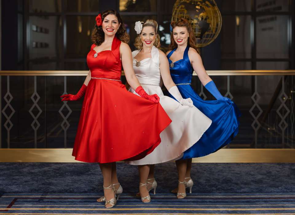 Photo of the Victory Belles singing trio dressed in red, white, and blue 1940's dresses.